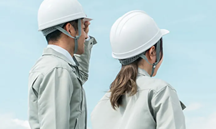 現場で打ち合わせをするヘルメット着用の2人の作業員