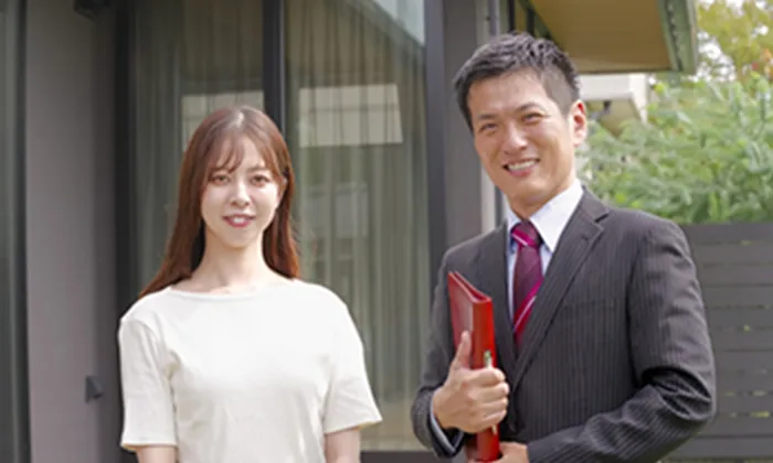 営業担当者と顧客が書類を手に笑顔で立つ様子