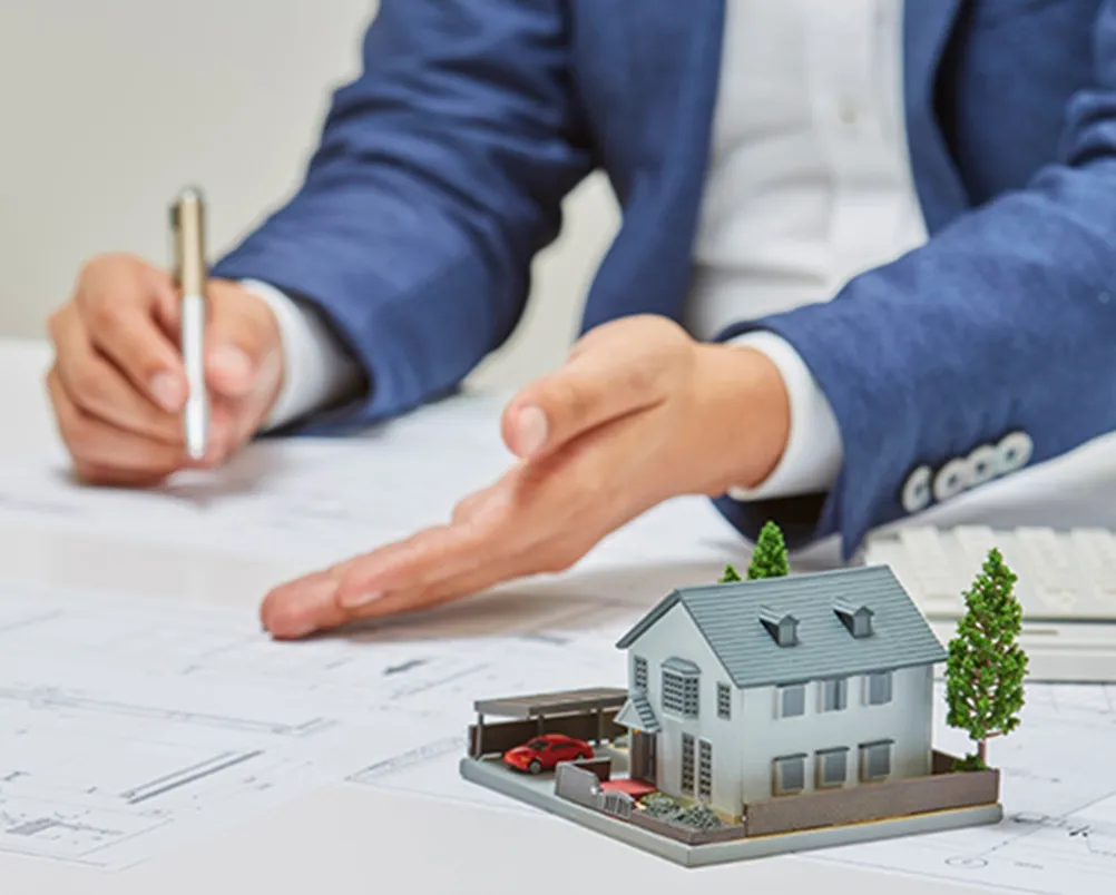 建築設計図と住宅模型を用いて説明する専門家の手元