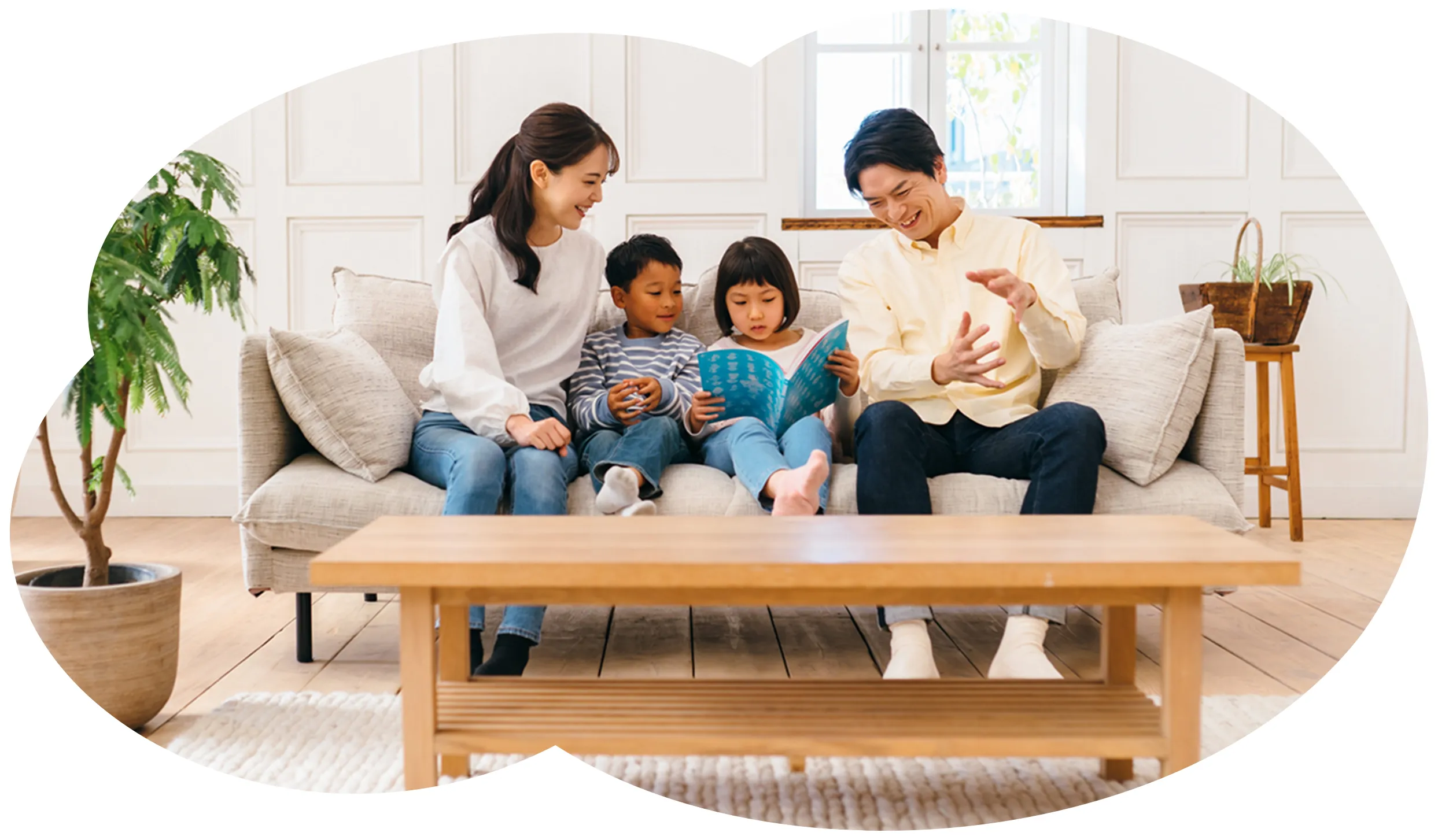 リビングのソファで本を読む家族4人（父・母・息子・娘）