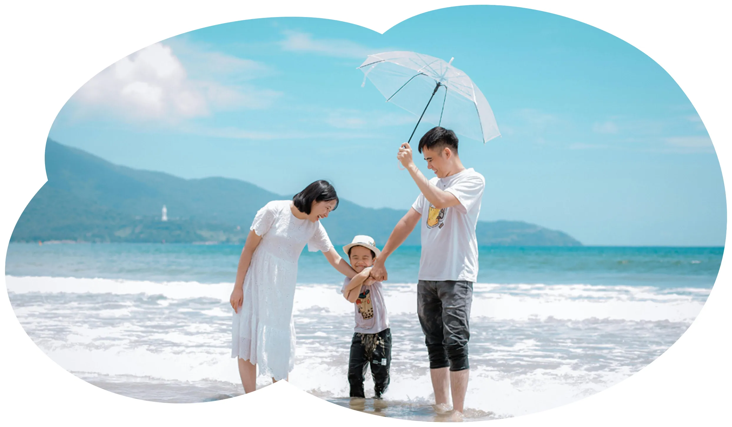 海辺で手をつなぐ家族3人（父・母・息子）、日差し除けの傘