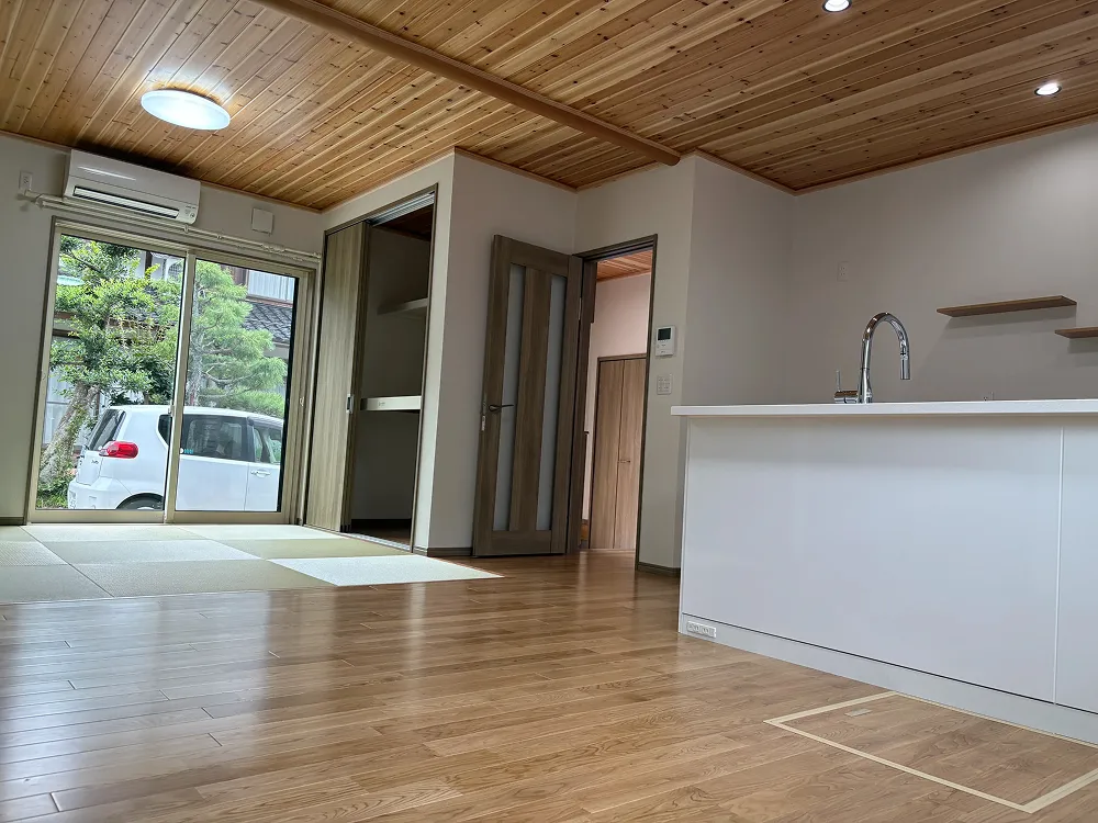 木目調のフローリングと天井が特徴のモダンなリビングダイニングキッチンスペース