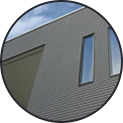 薄い緑がかったグレーの横張りサイディングと細長い窓のある外壁