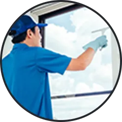 青い制服・帽子・手袋姿の人が窓をスクイージーで清掃（ハウスクリーニング）