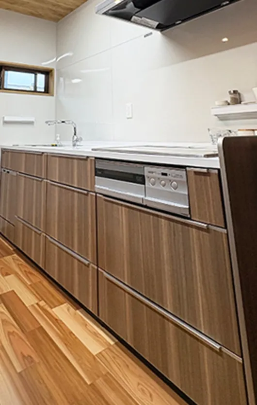 木目調キャビネットと食洗機、白いカウンターとステンレス蛇口のあるモダンなキッチン