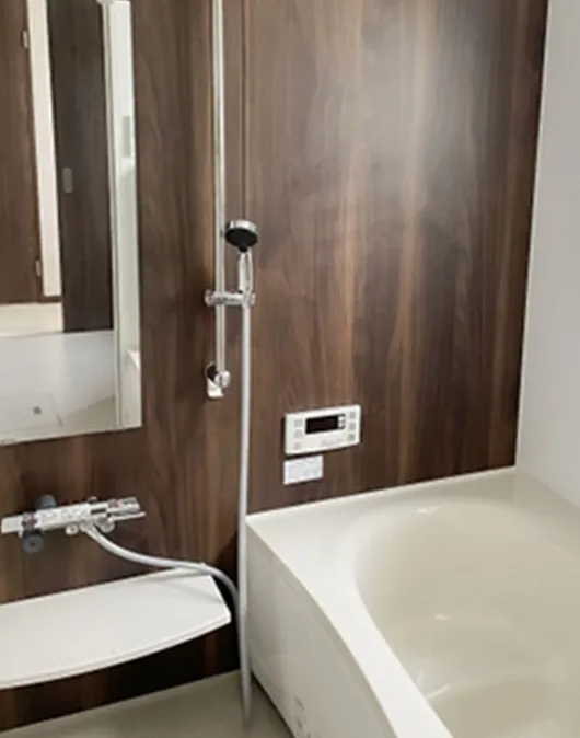 白い深めの浴槽と木目調壁、シャワー付きのモダンな浴室